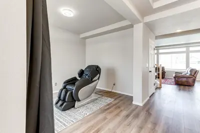 a living room with a chair sitting on a rug at 17 Mi to Downtown Denver Modern Aurora Home! in Aurora