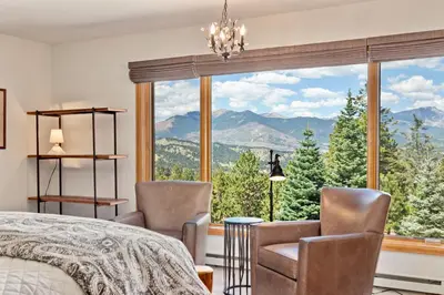 a bedroom with a bed and chairs and a large window at Aspen Spirit Vacation Home at Windcliff home in Estes Park