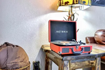 a red suitcase sitting on a table with a tv at Family & Dog Welcoming Lodge with Hot Tub & Games in Nederland
