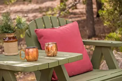 a picnic table with a pink pillow and two mugs at Family & Dog Welcoming Lodge with Hot Tub & Games in Nederland