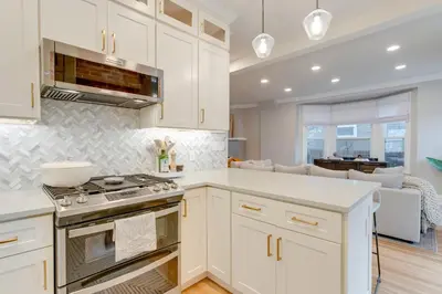 a kitchen with white cabinets and a stove top oven at Hot Tub, Fire Pits Ideally Located Denver Home! in Denver