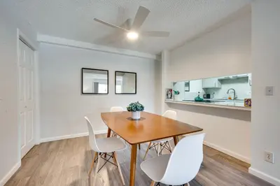 a dining room with a wooden table and white chairs at Cozy Westminster Condo 14 Mi to Downtown Denver! in Westminster