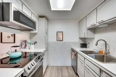 a kitchen with white cabinets and a sink at Cozy Westminster Condo 14 Mi to Downtown Denver! in Westminster