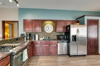 a kitchen with wooden cabinets and a clock on the wall at 13 Mi to Winter Park Mtn-View Granby Cabin in Granby