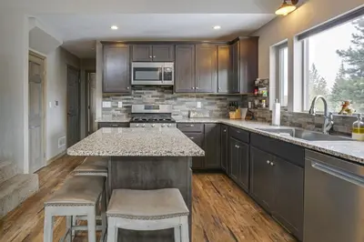 a kitchen with wooden cabinets and a counter with stools at Hike and Ski Grand Lake Cabin with Mtn-View Deck in Grand Lake