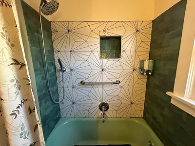 a bathroom with a green tub and a tile wall at Charming 1920s Retreat Modern Kitchen 5 minutes to Dining and Med District in Denver