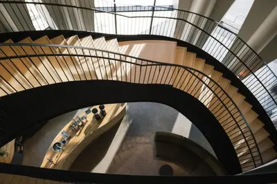 a spiral staircase in a building with cars on it at Populus in Denver