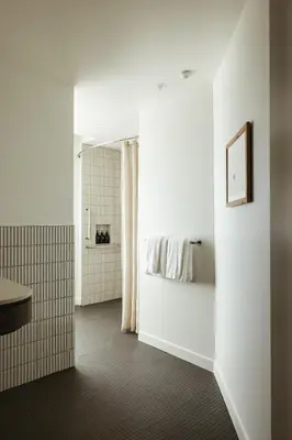 a white bathroom with a bed and a shower at Populus in Denver