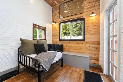 a tiny house with a bed in a room with wooden walls at Riverside Colorado in Bellvue