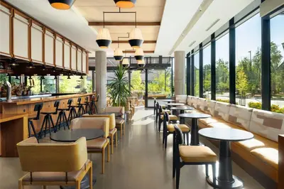 a restaurant with tables and chairs and windows at Moxy Boulder University in Boulder
