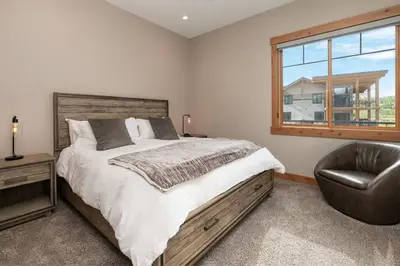 a bedroom with a bed and a chair and a window at NEW Condo Grand Park W/Hot Tub & Mountain View in Fraser