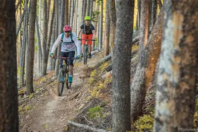 two people riding bikes on a trail in the woods at NEW Condo Grand Park W/Hot Tub & Mountain View in Fraser