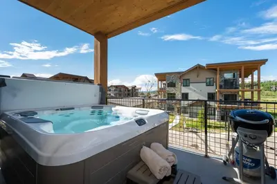 a hot tub on a balcony with a view of a house at NEW Condo Grand Park W/Hot Tub & Mountain View in Fraser