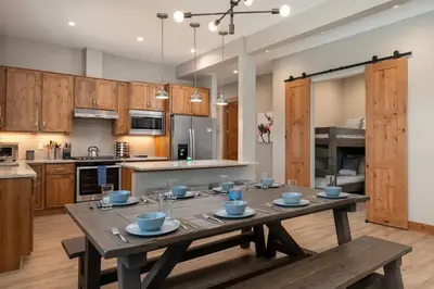 a large kitchen with a wooden table with blue bowls on it at NEW Condo Grand Park W/Hot Tub & Mountain View in Fraser