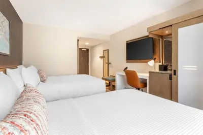 a hotel room with two beds and a desk at Cambria Hotel Denver Downtown RiNo in Denver
