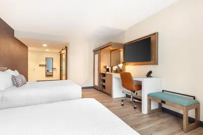 a hotel room with two beds and a desk at Cambria Hotel Denver Downtown RiNo in Denver