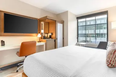 a hotel room with a bed and a desk and a tv at Cambria Hotel Denver Downtown RiNo in Denver