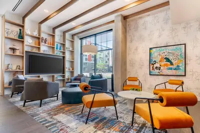 a living room with a tv and chairs at Cambria Hotel Denver Downtown RiNo in Denver