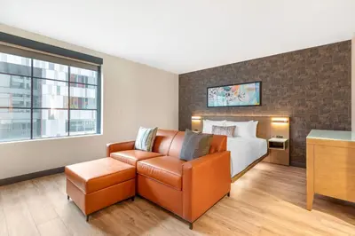 a hotel room with a bed and a couch and a chair at Cambria Hotel Denver Downtown RiNo in Denver