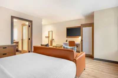a hotel room with a bed and a living room at Cambria Hotel Denver Downtown RiNo in Denver