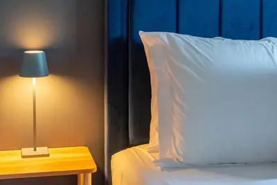 a bed with a white pillow and a table with a lamp at Downtown Denver: 4bd - Game/Movie Room - Backyard in Arvada
