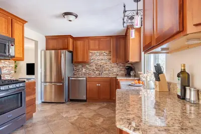 a kitchen with wooden cabinets and a stainless steel refrigerator at Downtown Denver: 4bd - Game/Movie Room - Backyard in Arvada
