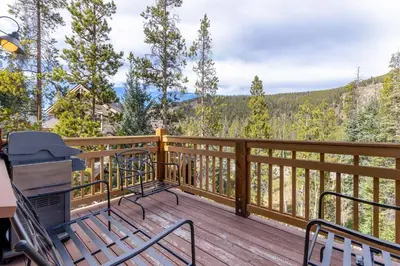 a deck with two chairs and a grill on it at 6554 Settlers Creek townhouse in Keystone