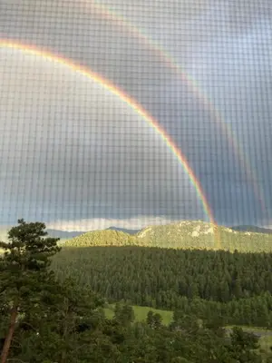 a rainbow in the sky over a forest at Colorado Bed & Breakfast with beautiful views in Evergreen