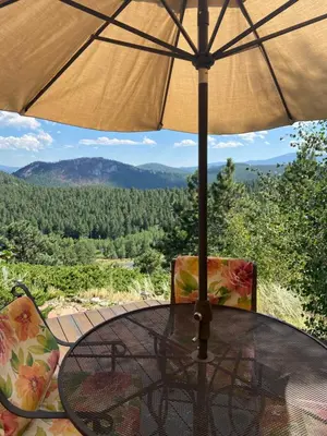 a table and chairs with an umbrella on a balcony at Colorado Bed & Breakfast with beautiful views in Evergreen
