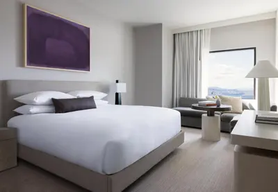 a bedroom with a large white bed and a living room at Kimpton Claret Hotel by IHG in Denver
