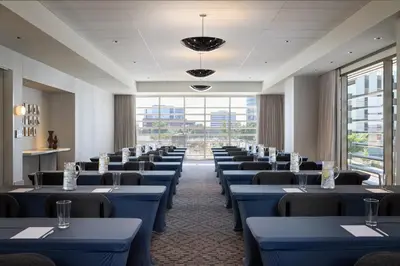 a row of tables and chairs in a room with windows at Kimpton Claret Hotel by IHG in Denver