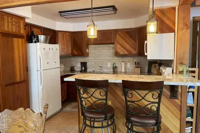 a kitchen with a white refrigerator and two bar stools at Shady Pines- Cozy Mountain Retreat in Idaho Springs