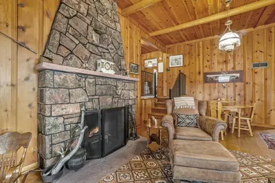 a living room with a stone fireplace in a cabin at Hidden Pines -- EV#3034 home in Estes Park