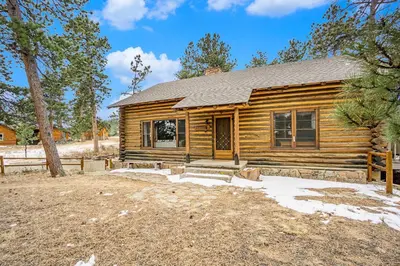 a log cabin with a yard in front of it at Hidden Pines -- EV#3034 home in Estes Park