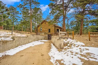 a log cabin in the woods with a dirt road at Hidden Pines -- EV#3034 home in Estes Park