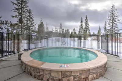 a hot tub in a stone circle in front of a fence at Downtown Winter Park Condo about 3 Mi to Skiing! in Winter Park