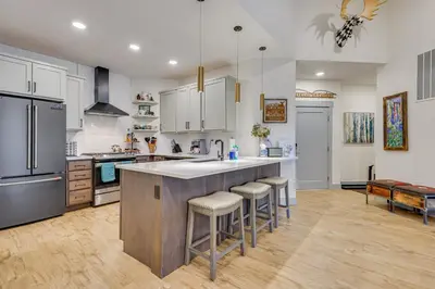 a kitchen with a large island with bar stools at Downtown Winter Park Condo about 3 Mi to Skiing! in Winter Park