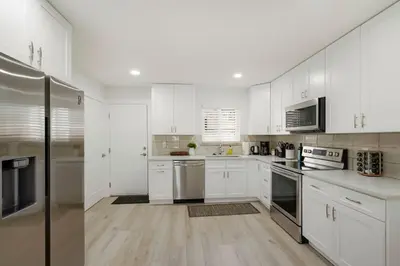 a kitchen with white cabinets and stainless steel appliances at 5-Bedrooms! Stylish and Modern Home, Pets Welcome! in Arvada