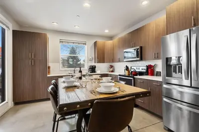 a kitchen with a wooden table and a stainless steel refrigerator at Elegant Oasis - Fireplaces, King Beds, Mtn Views! in Fort Collins