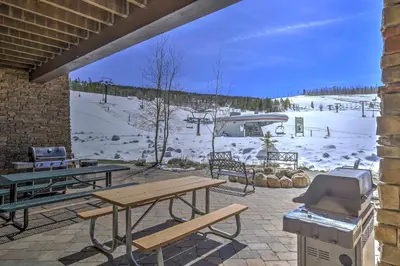 a patio with a grill and picnic tables and a snow covered field at Granby Retreat with Community Pool Ski-InandSki-Out! in Granby