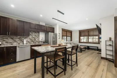 a kitchen with wooden cabinets and a island with bar stools at Premium Unit 1301 - 1 Bedroom - Zephyr Mtn Lodge condo in Winter Park