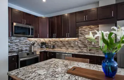 a kitchen with wooden cabinets and a vase of flowers on a table at Premium Unit 1301 - 1 Bedroom - Zephyr Mtn Lodge condo in Winter Park