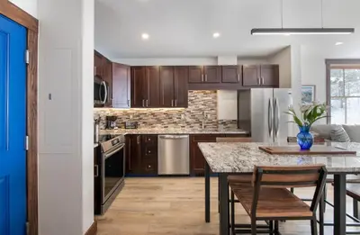 a kitchen with wooden cabinets and a table and chairs at Premium Unit 1301 - 1 Bedroom - Zephyr Mtn Lodge condo in Winter Park
