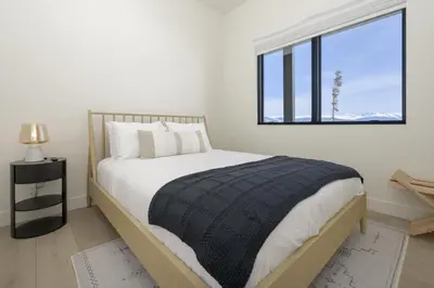 a white bedroom with a large bed with a window at Sky House chalet in Tabernash