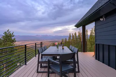 a table and chairs on a deck with a view at Sky House chalet in Tabernash