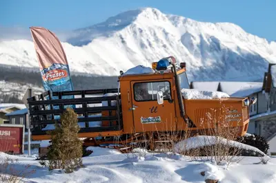 an orange truck parked in the snow with a snow covered mountain at Sunnyside Up in Fraser