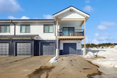 a white house with a balcony and two garage doors at Sunnyside Up in Fraser