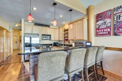 a kitchen with a bar with bar stools at 4 Mi to Ski Dillon Condo with Balcony and Mtn Views in Dillon