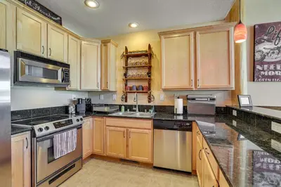a kitchen with wooden cabinets and black counter tops at 4 Mi to Ski Dillon Condo with Balcony and Mtn Views in Dillon