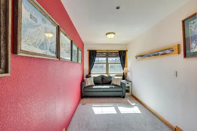 a living room with a red wall and a couch at 4 Mi to Ski Dillon Condo with Balcony and Mtn Views in Dillon